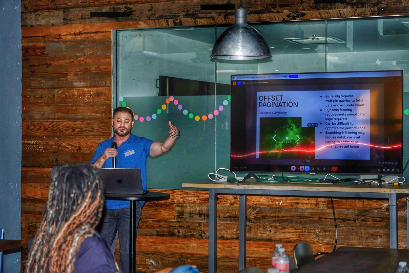 A speaker presenting at PySanAntonio 2025 with slides behind him