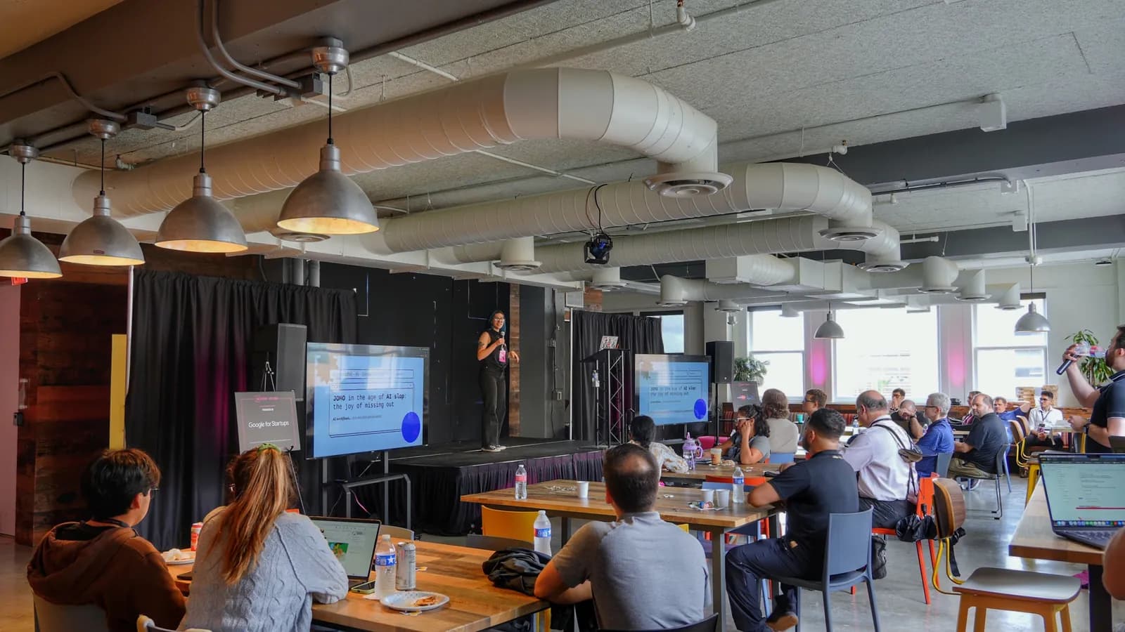 The PySanAntonio room at Geekdom — a speaker presenting at the screen with the audience at long tables, laptops open